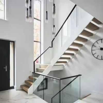 Escalier flottant en fer et en acier à l' intérieur moderne, avec une rampe en bois et une balustrade en verre, pour les commerces et les appartements